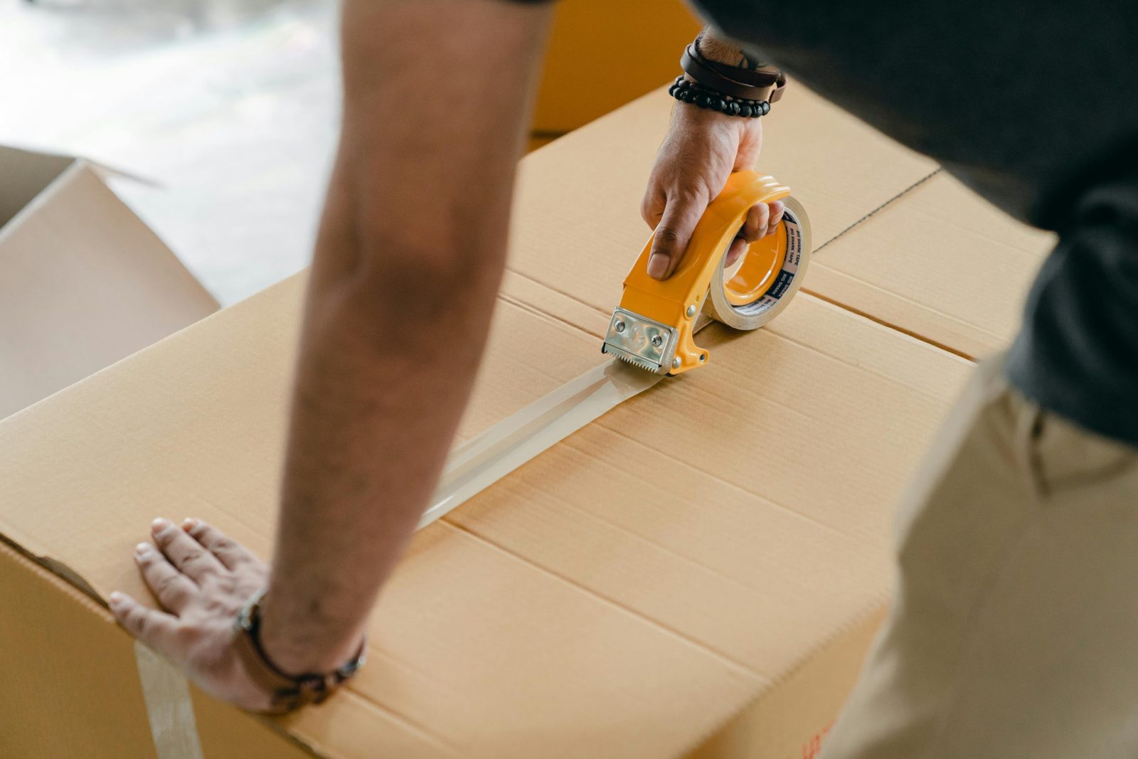 Man Using Duct Tape to Seal a Cardboard Box.