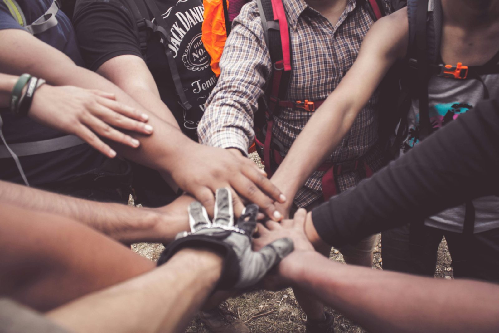 A group of diverse individuals join hands for teamwork.