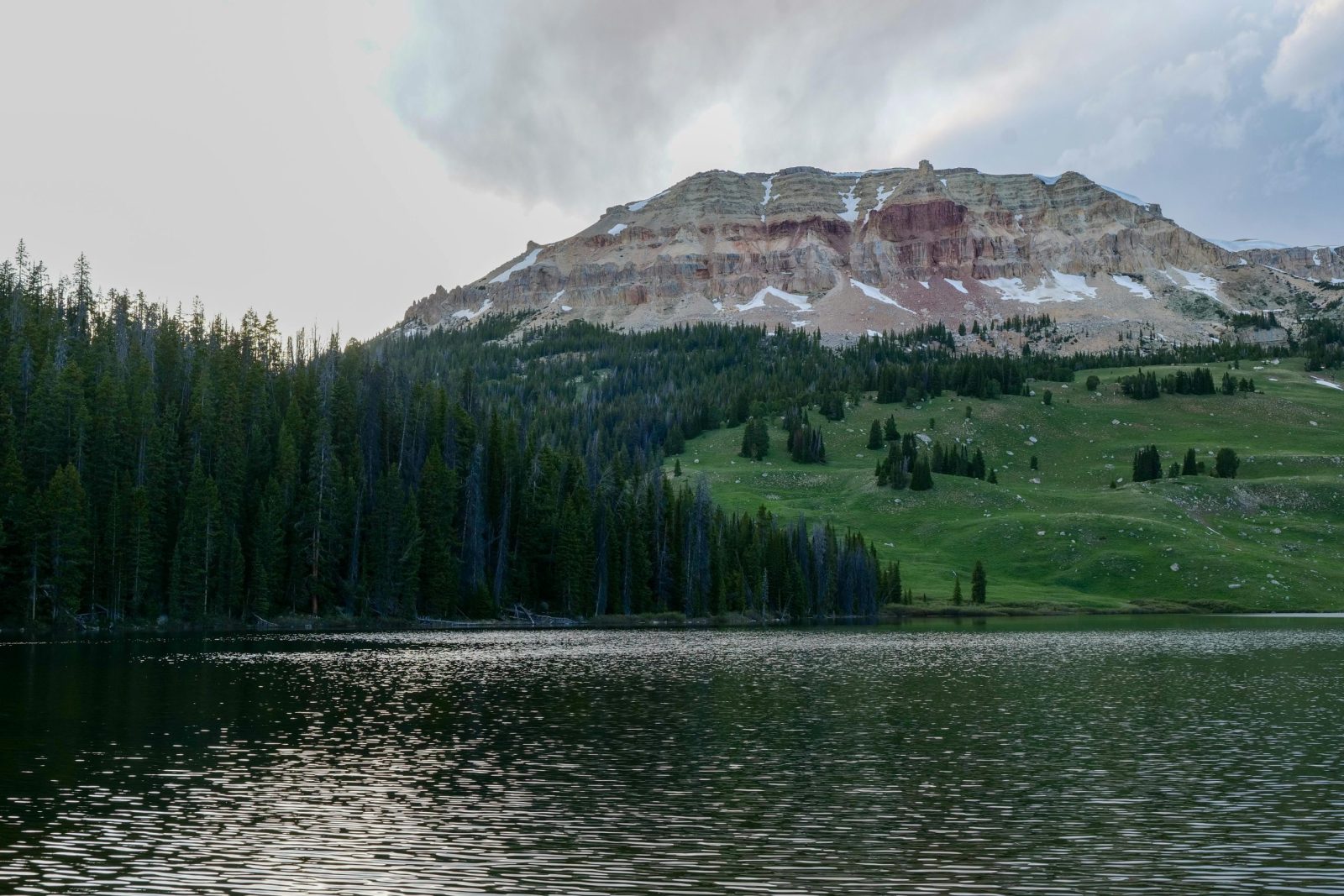 Breathtaking view of Yellowstone's mountains and lake under a cloudy sky.