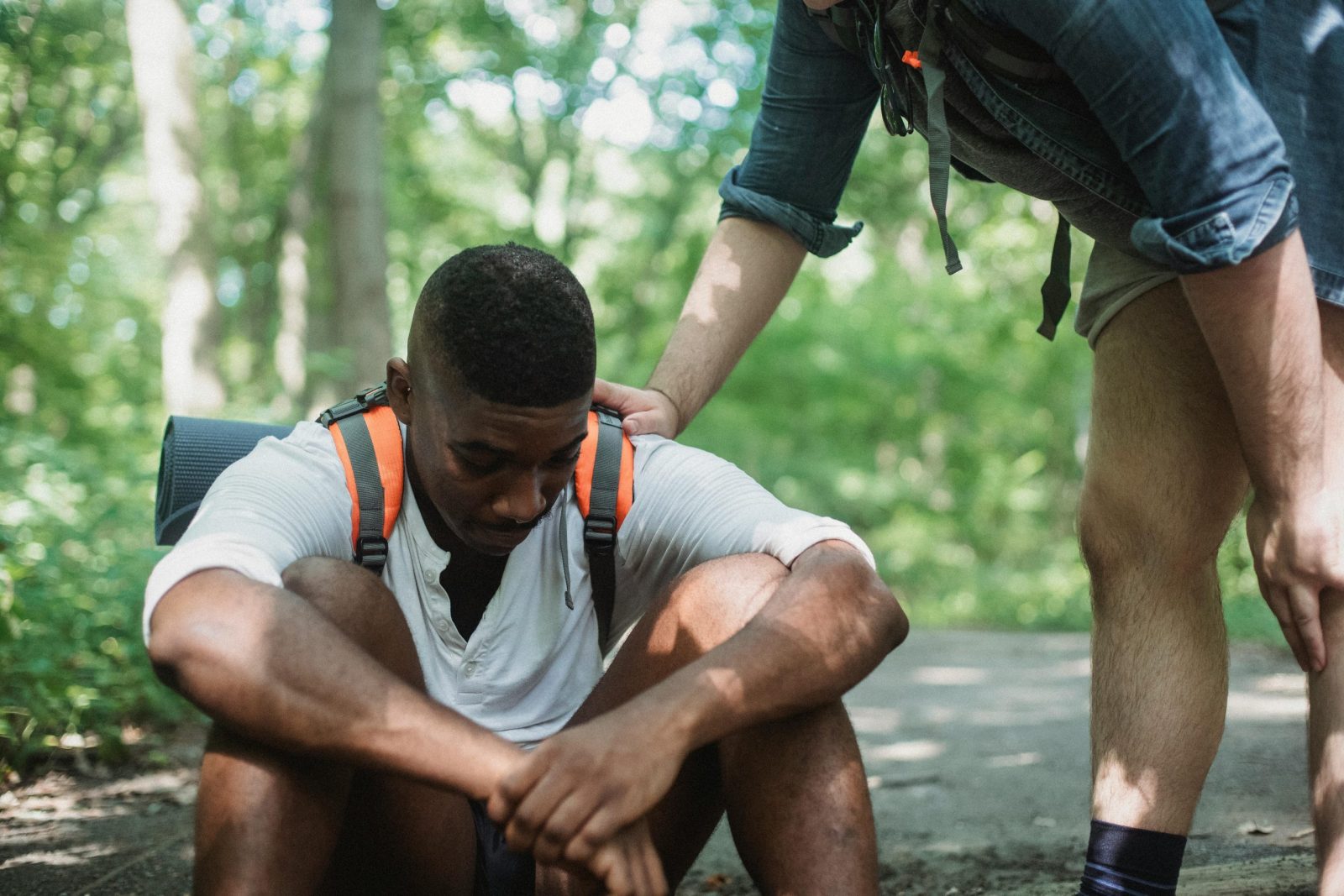 Two friends taking a break on a hiking trail, providing emotional support in a forest.