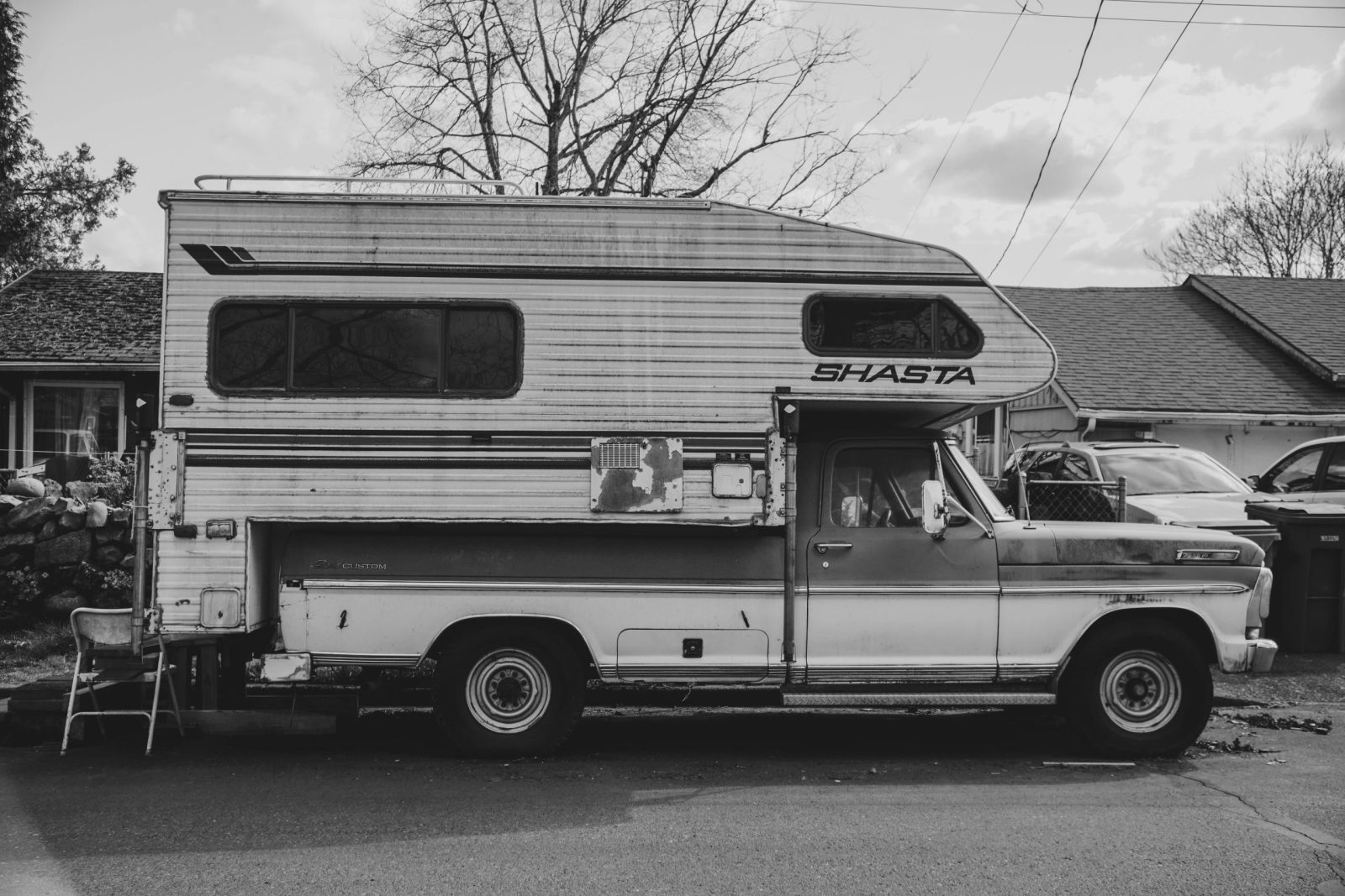 Classic black and white photo of a vintage Shasta camper truck parked outdoors.