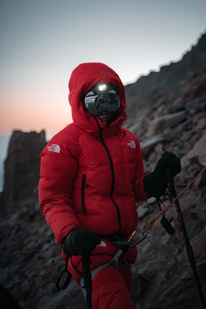 A man in a red jacket standing on a rocky mountain
