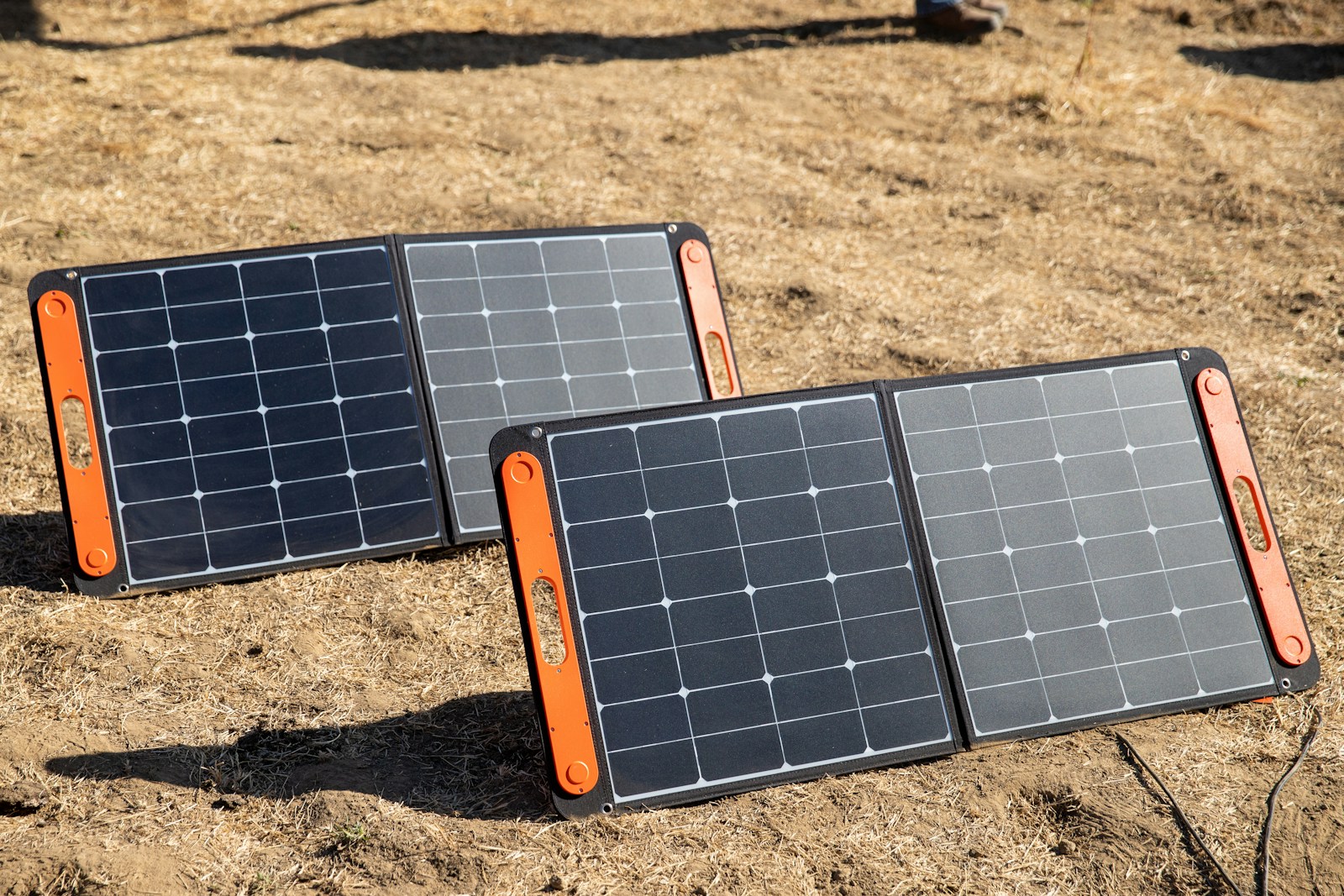 A couple of black and orange rectangular objects on a dirt surface