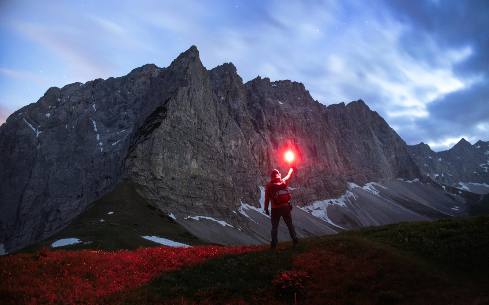 A lone hiker holds a red flare.