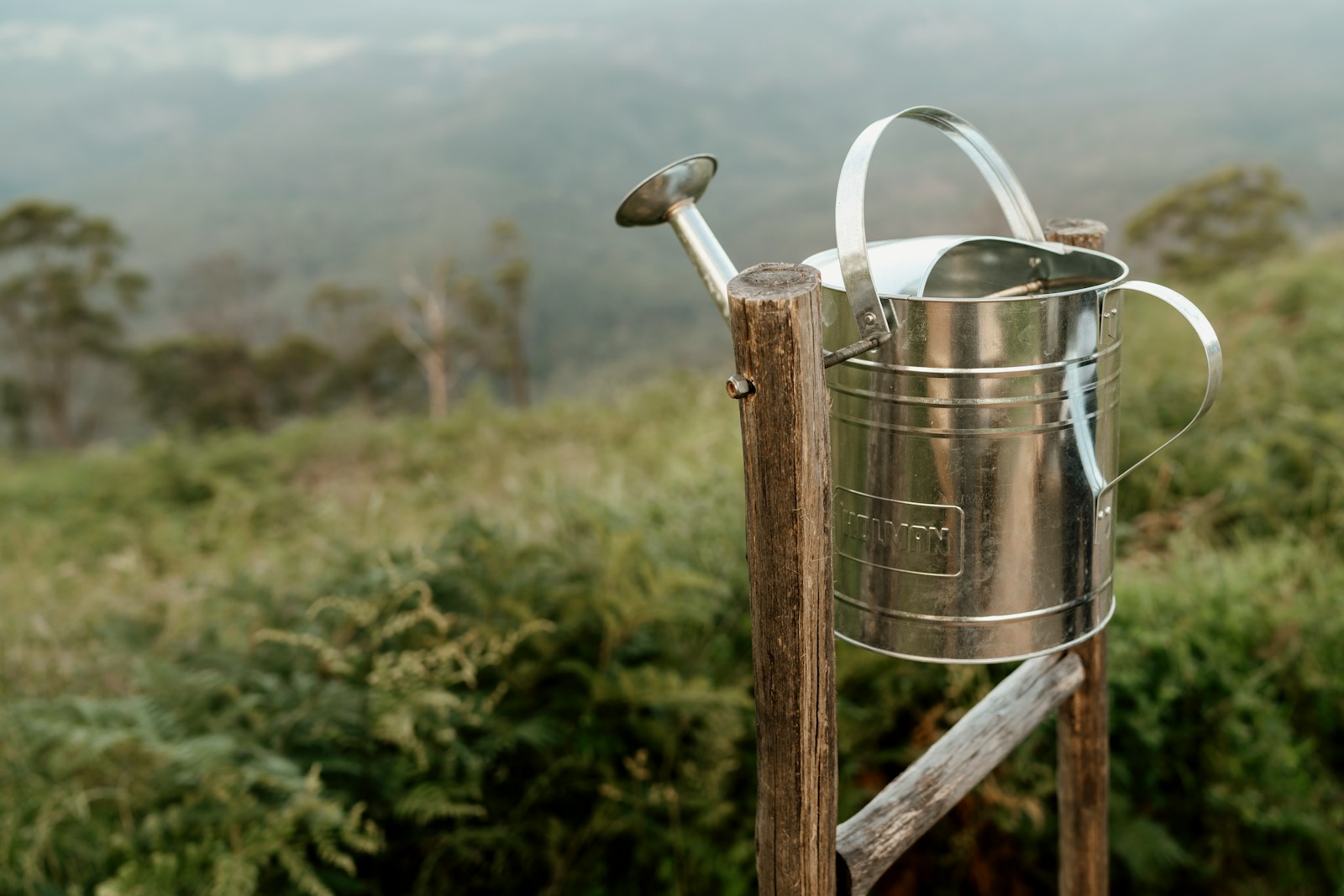 A metal bucket with a handle on a wooden post