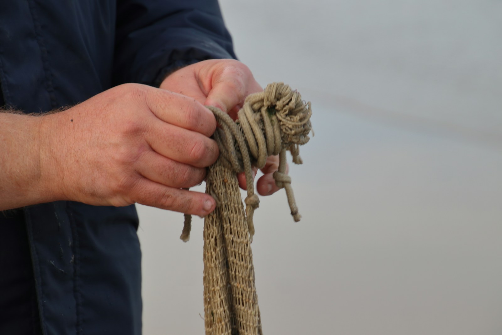 A person making brown rope.