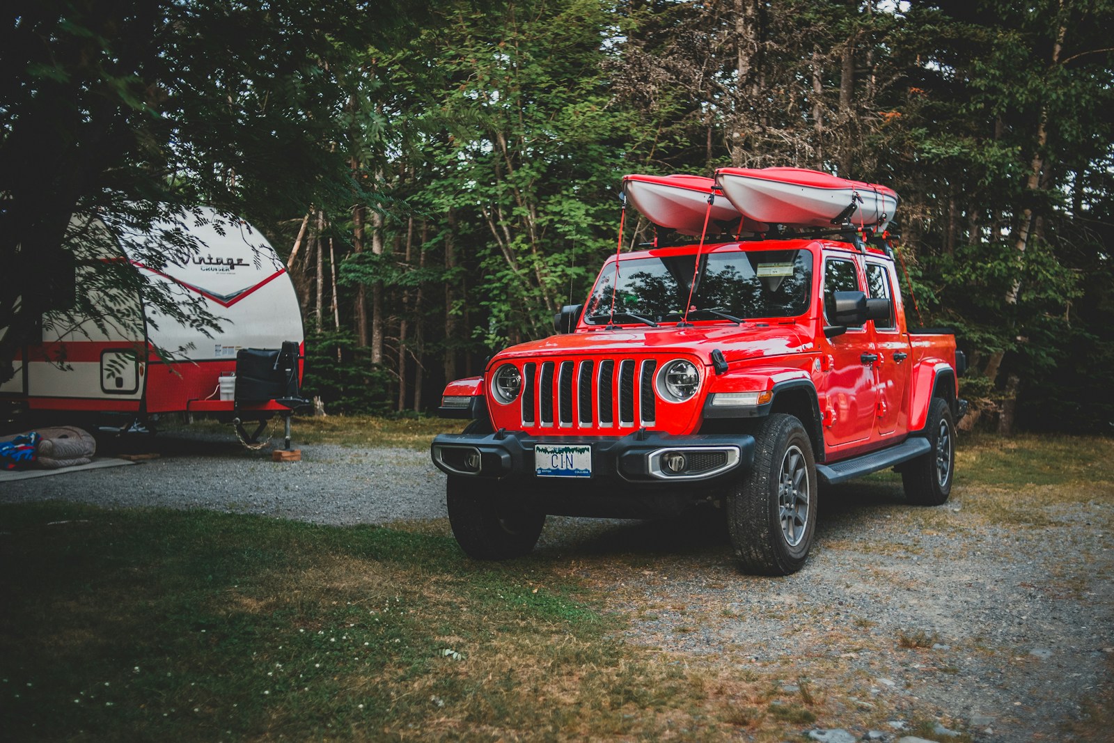 Red jeep wrangler parked near trees.