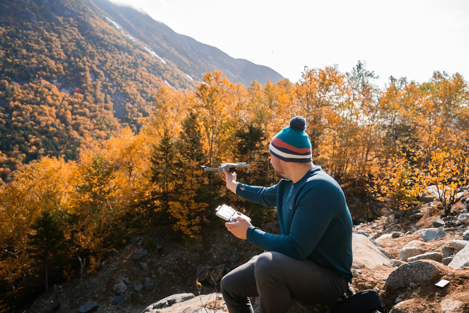 A man sitting on a rock with a drone