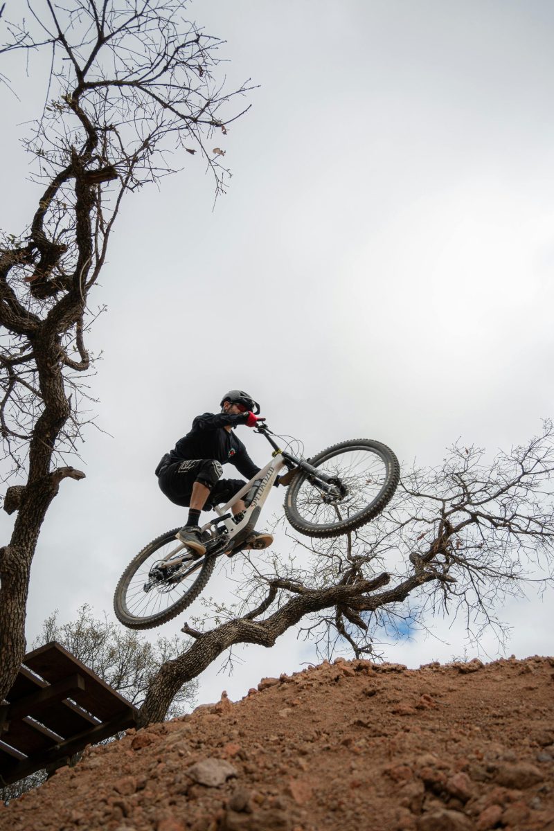 A thrilling moment of a biker jumping over a hill on a mountain bike trail, embracing adventure.