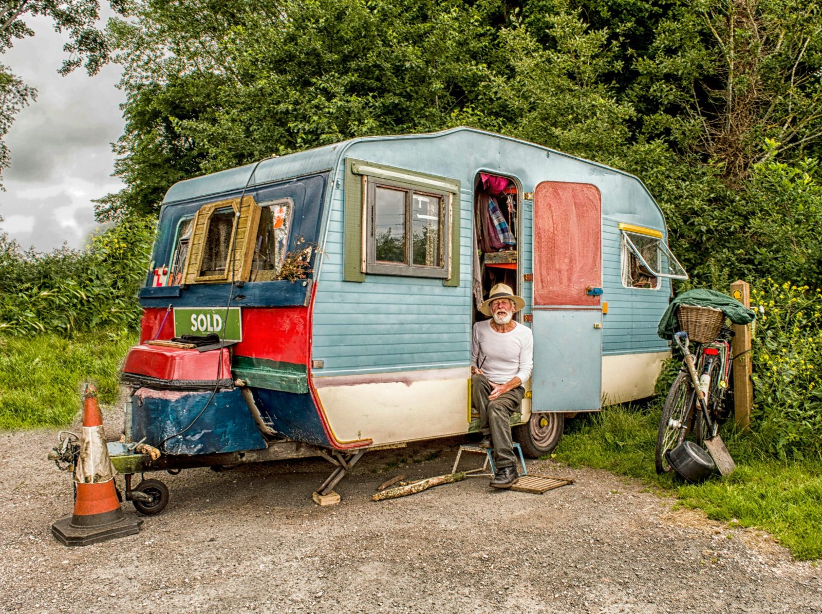Vintage caravan with elderly man outdoors in Devon, showcasing rustic lifestyle and travel.