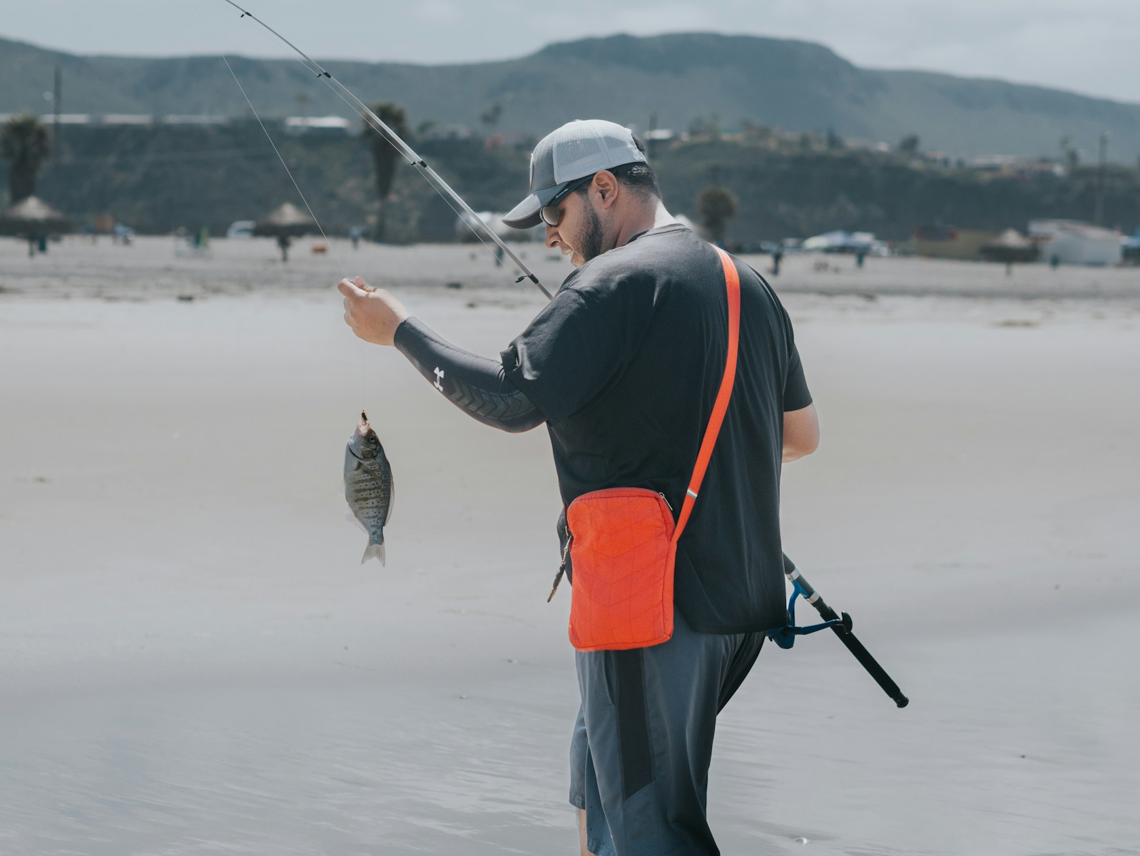 A man holding a fish while standing on a beach
