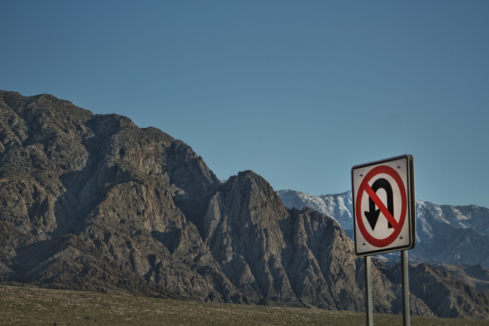 a no left turn sign in front of a mountain