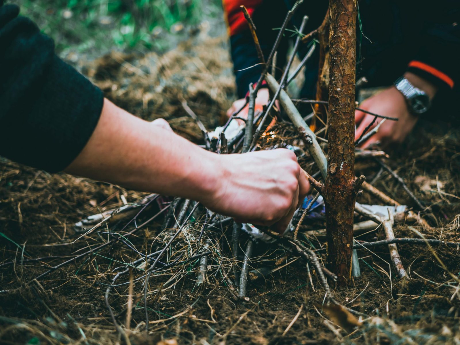 Close-up of hands arranging sticks to start a fire.