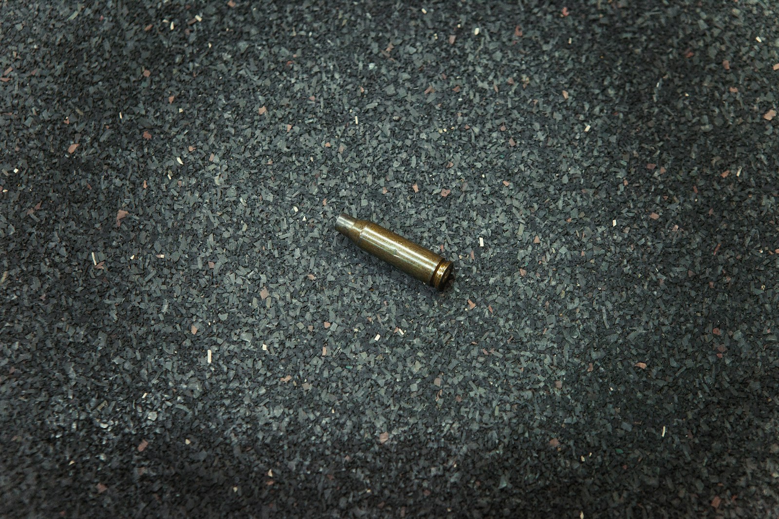 A bullet laying on the ground in the middle of the floor