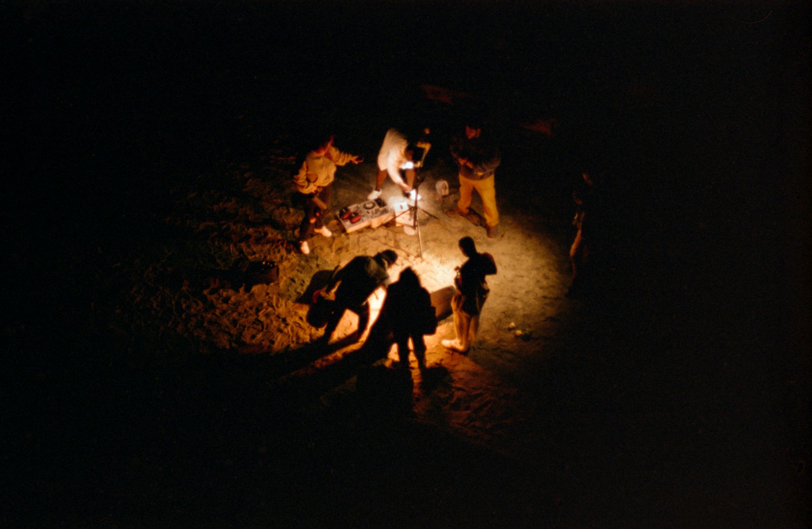 People gather around a campfire at night.