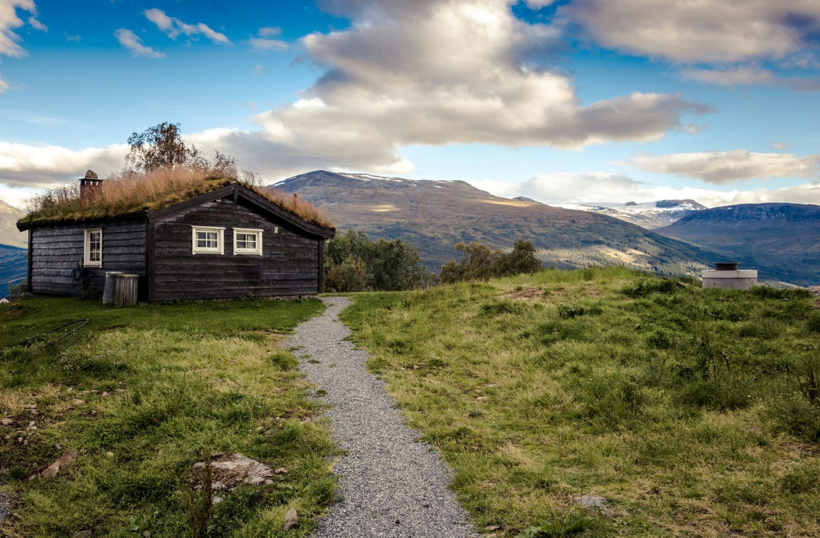 Idyllic rural cabin with grass roof set against breathtaking mountain landscape.