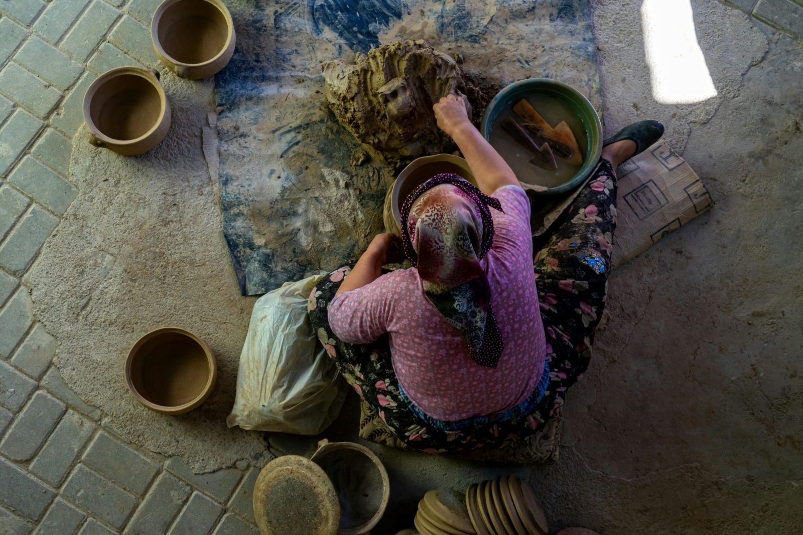 A female artisan skillfully crafting clay pots in a traditional setting, showcasing pottery artistry.