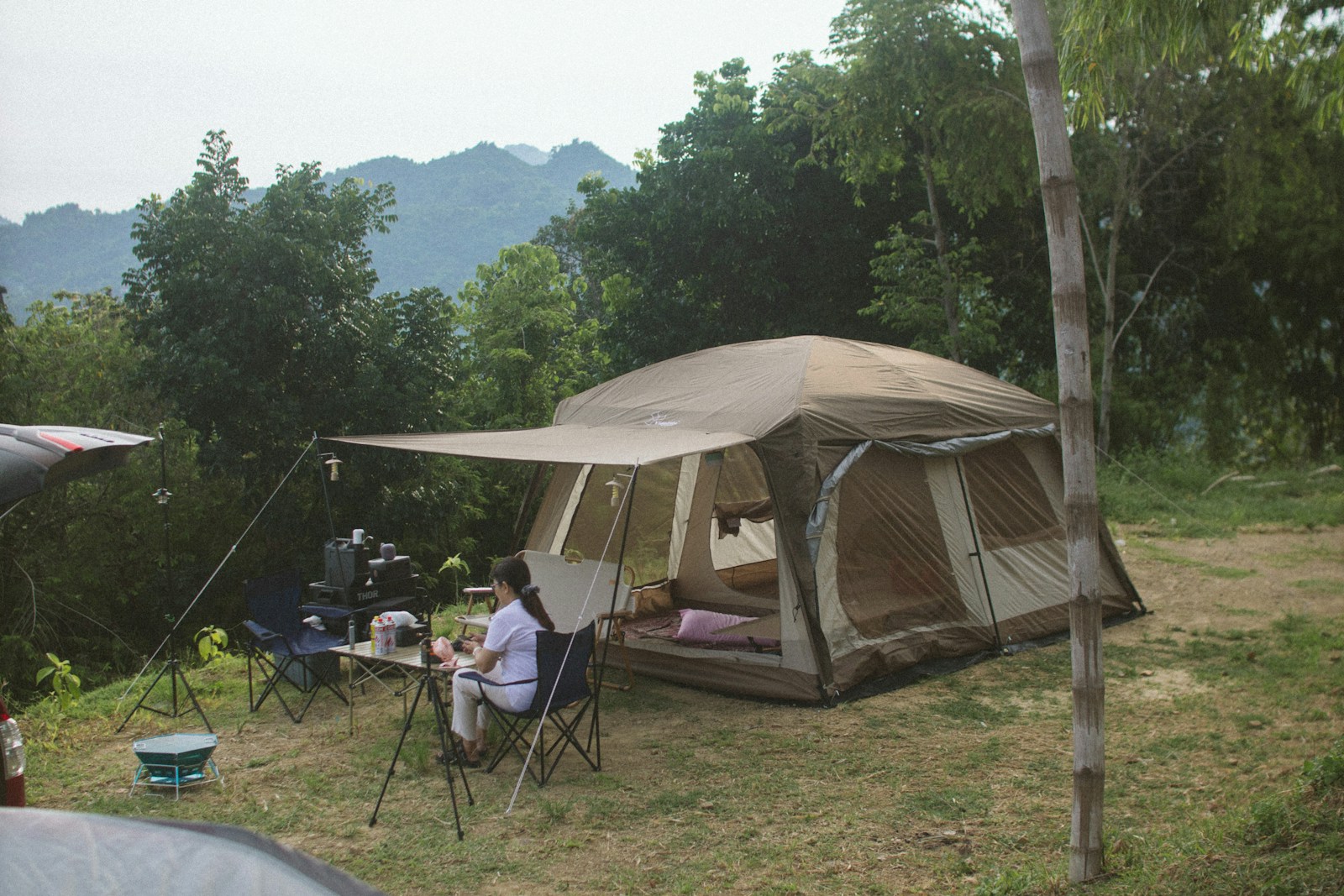 A Person Sitting at a Table outside Tent