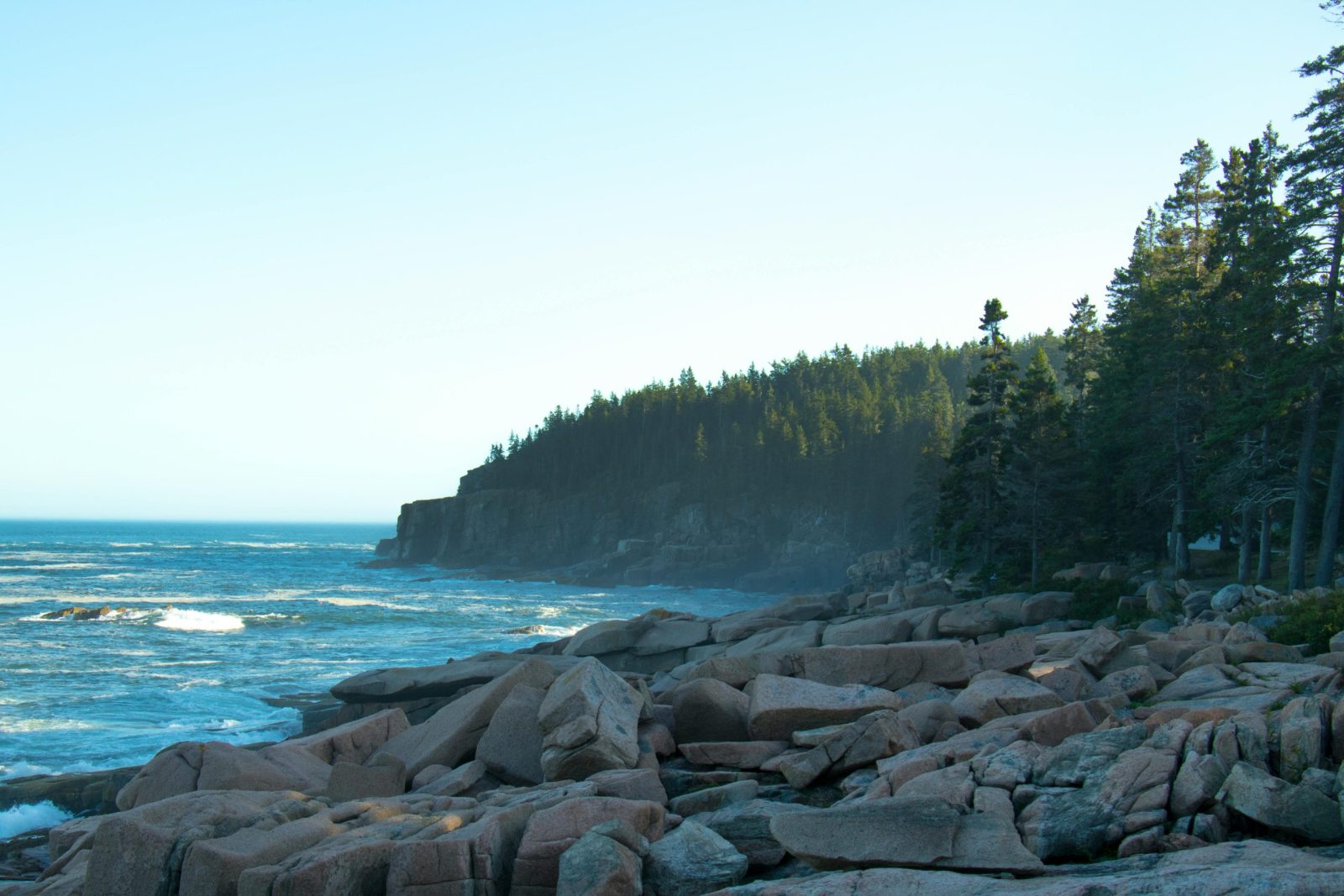Stunning view of the rocky Acadia coastline with ocean waves crashing against the shore at sunrise.