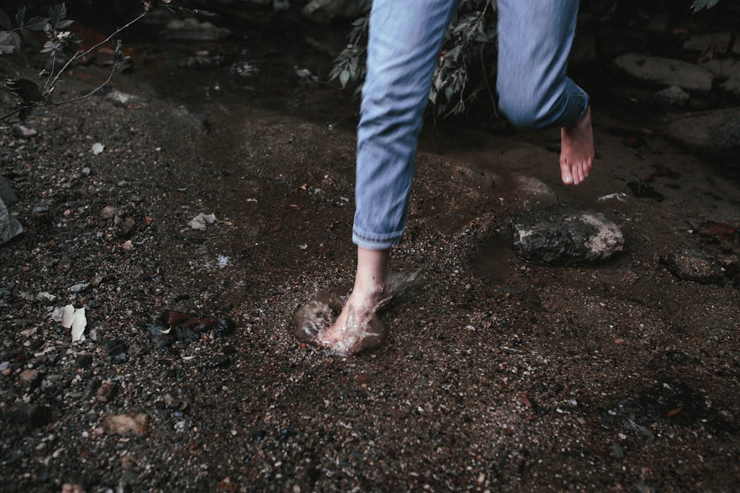 Person in Blue Denim Jeans Standing on Brown Soil