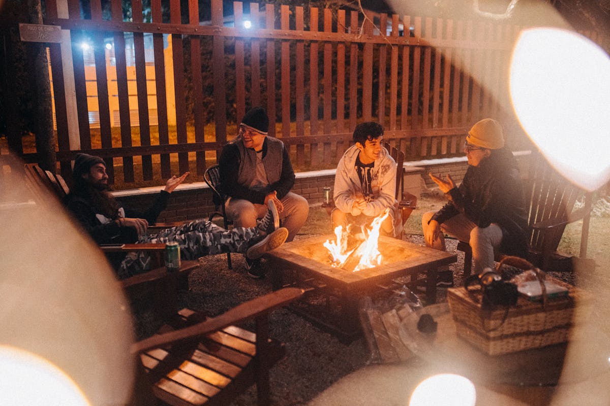 Smiling travelers talking against burning fire in camp at night
