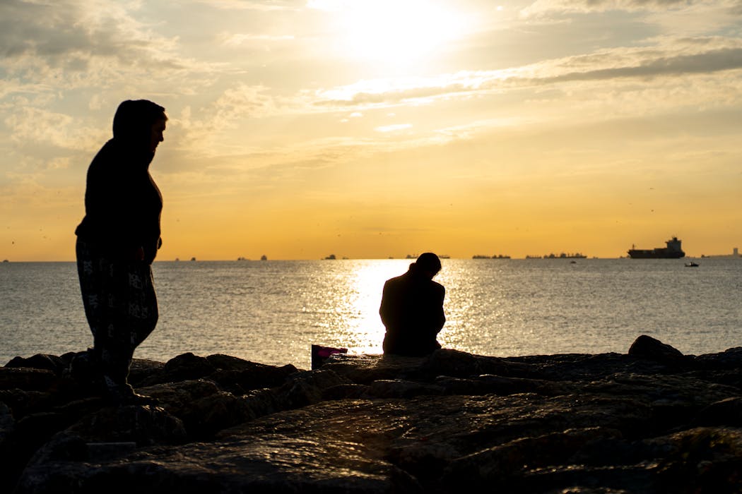 Silhouette of People by the Sea at Sunset