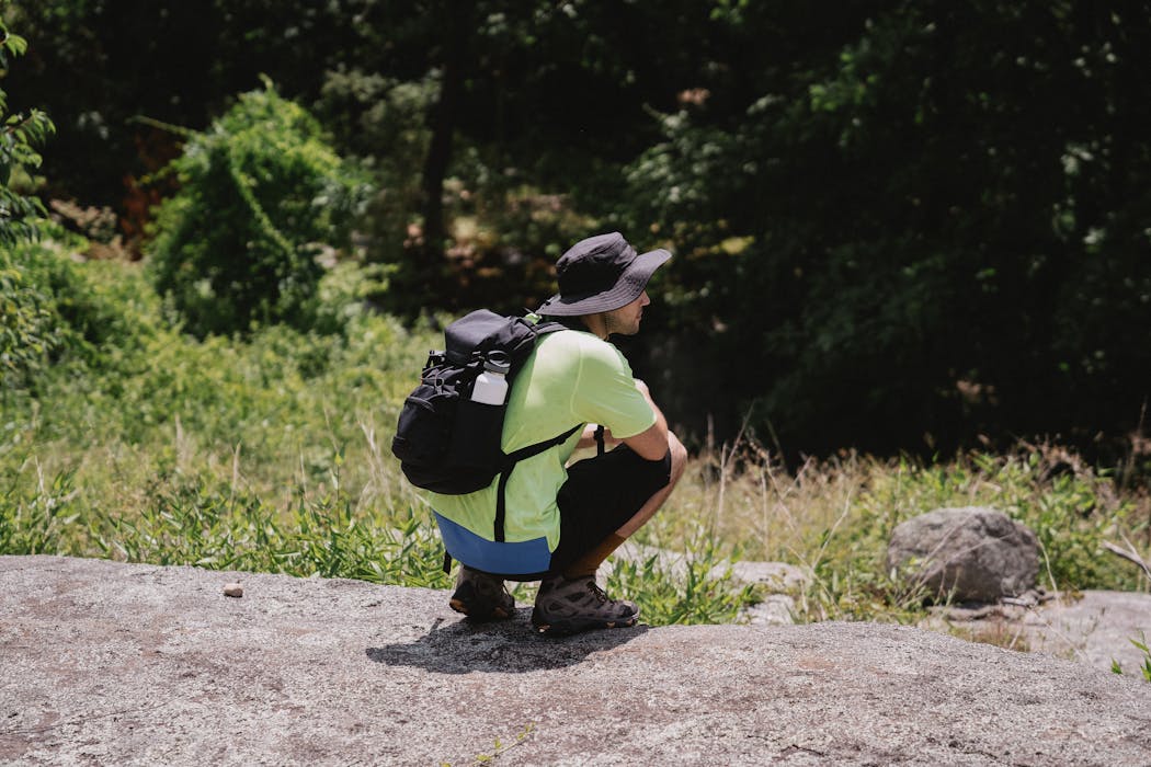 Man With Backpack Sitting on Floor Near Grass