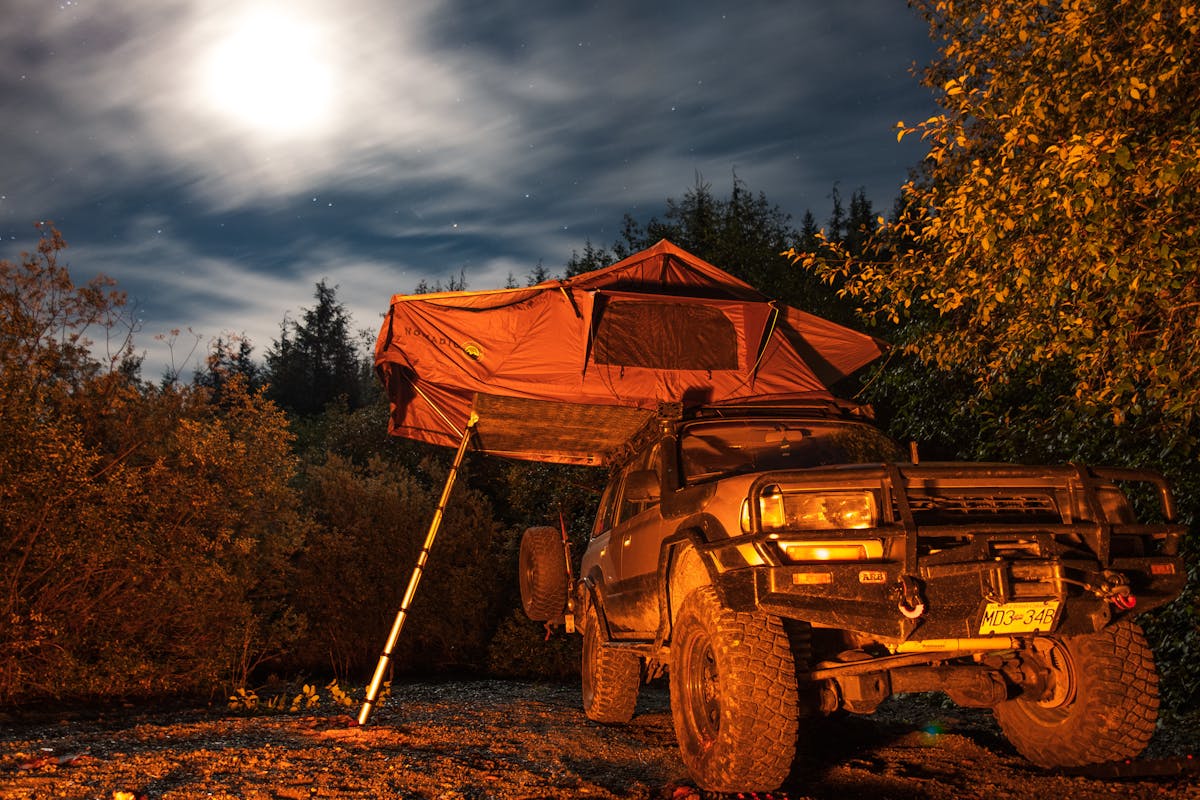 Photo of a Jeep and a Tent in Bushes at Night
