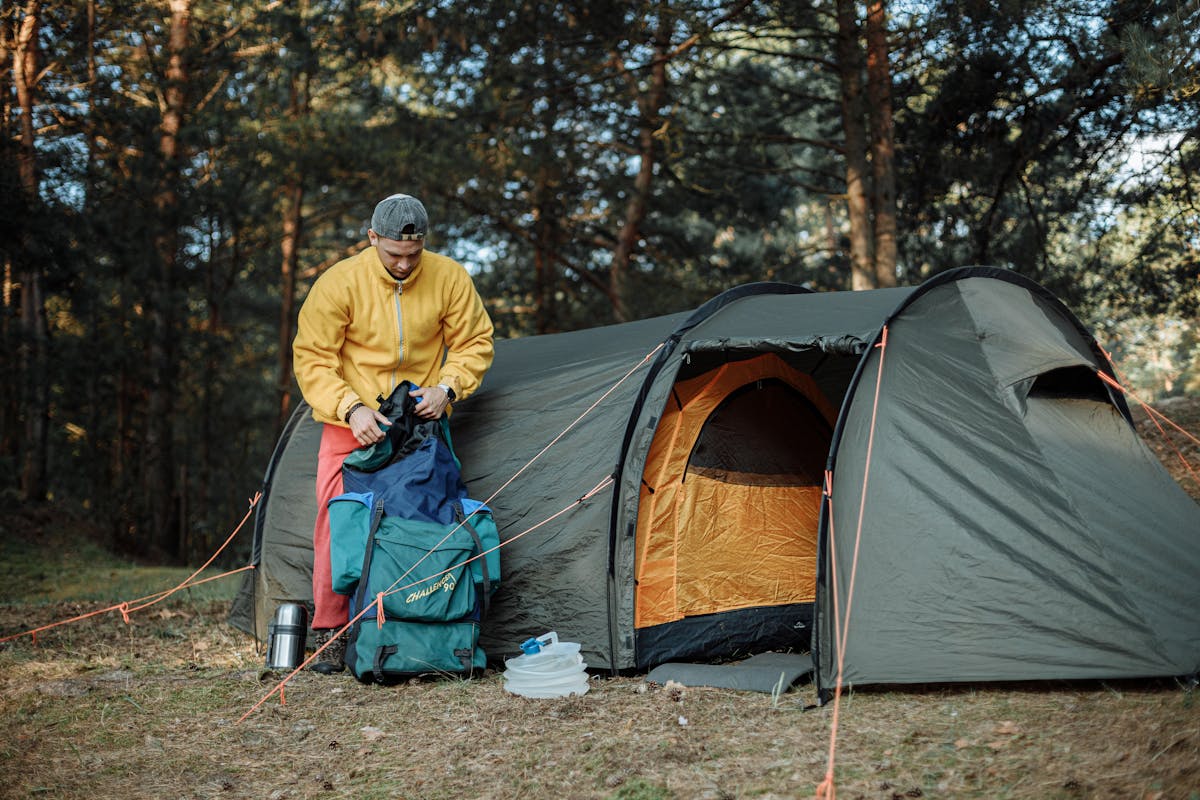 taiki-ishikawa-w6EMxsk8CDA-unsplash Man in Yellow Jacket and Blue Pants Standing Near Orange and Gray Dome Tent