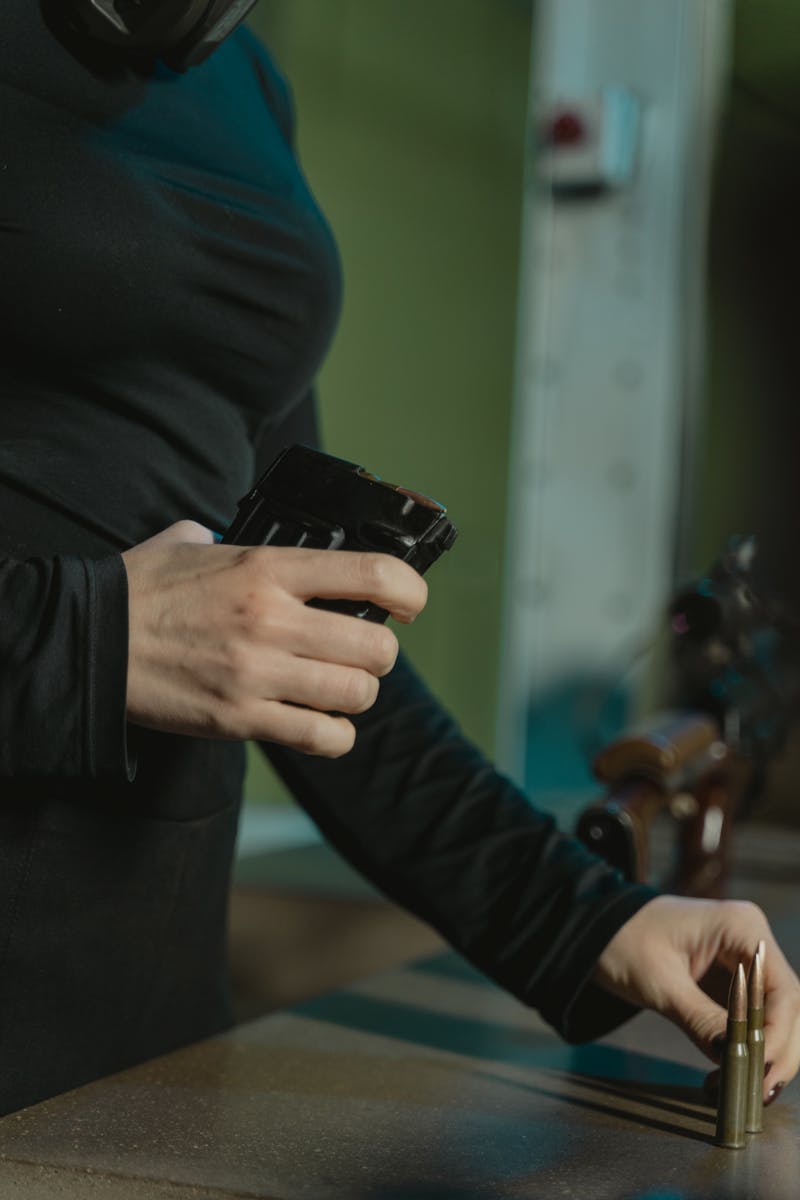 Person in Black Long Sleeve Shirt Holding a Black Rifle Magazine