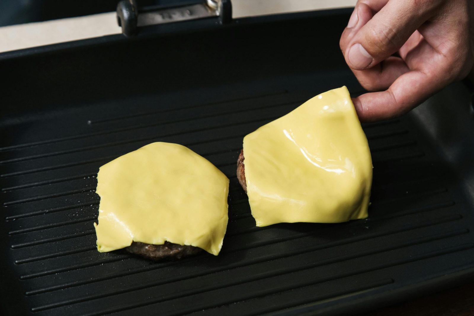 Delicious cheeseburgers being prepared on a grill. Perfect for food enthusiasts.