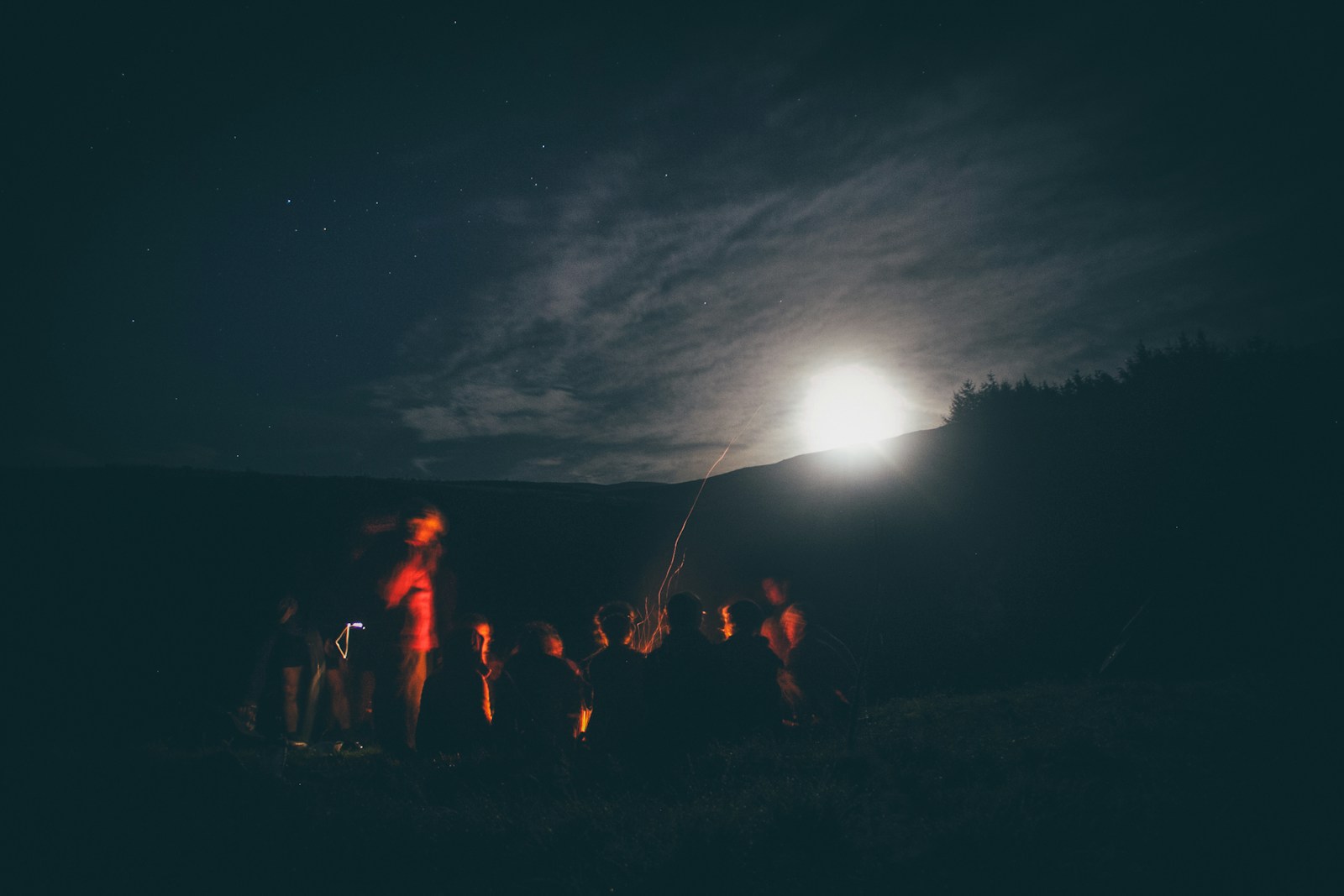 A group of people standing in the dark under a full moon