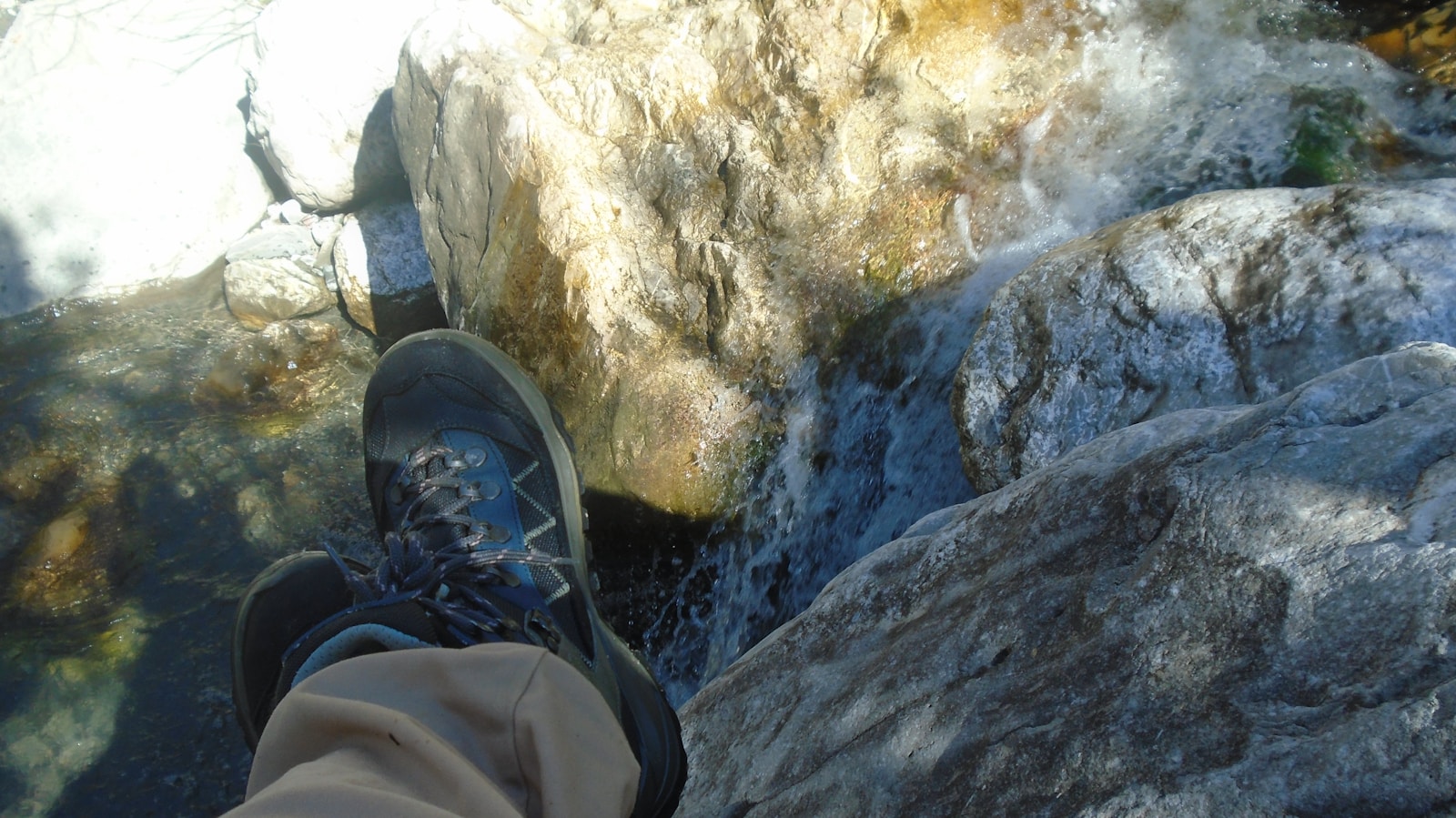 A person standing on top of a rock next to a river