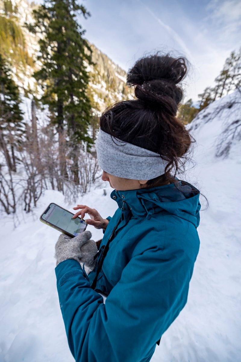 a woman standing in the snow looking at her cell phone