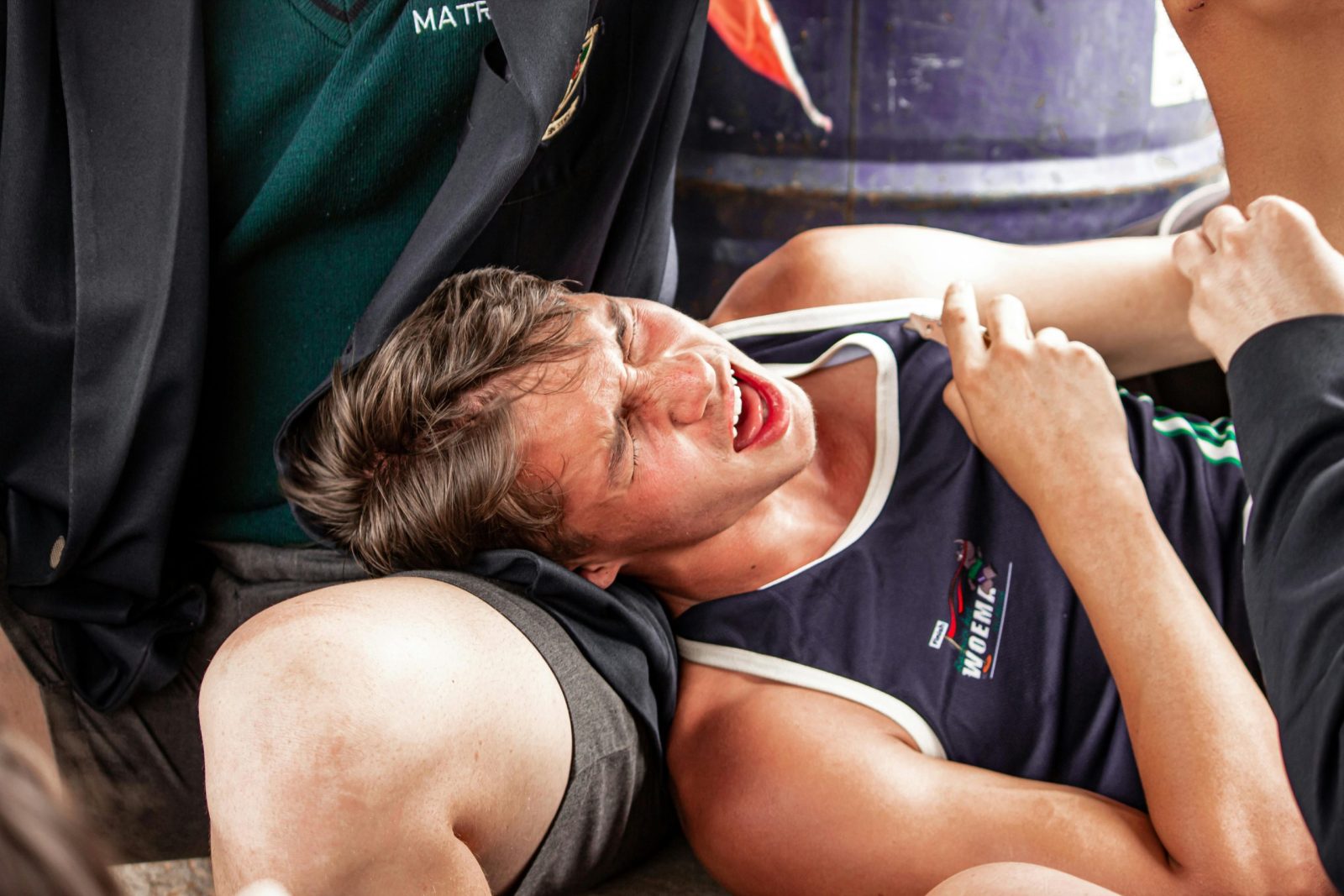 A young male athlete grimacing in pain due to muscle cramps during a sports event.