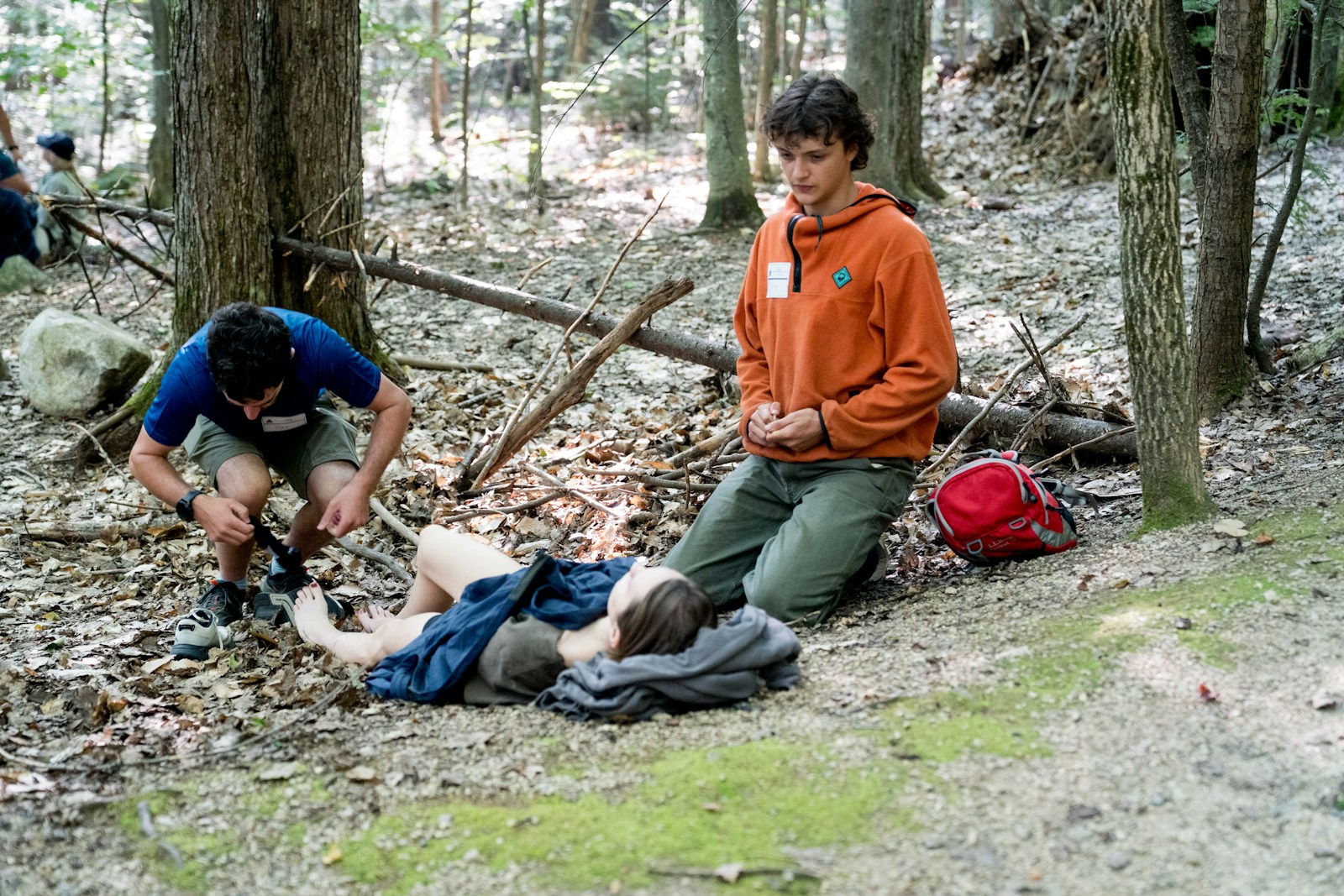 Three people resting in a forest clearing