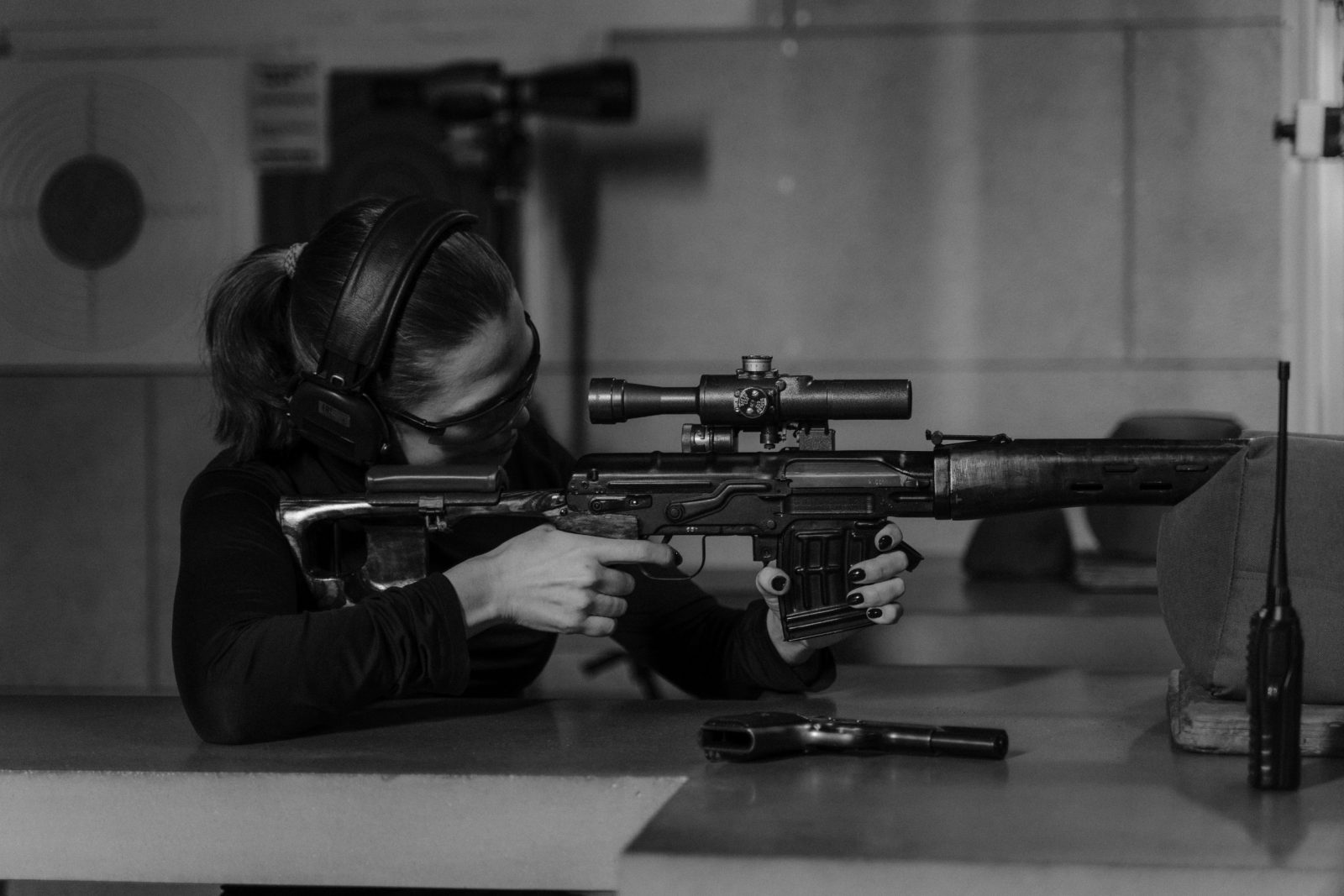Woman aiming rifle in shooting range. 
