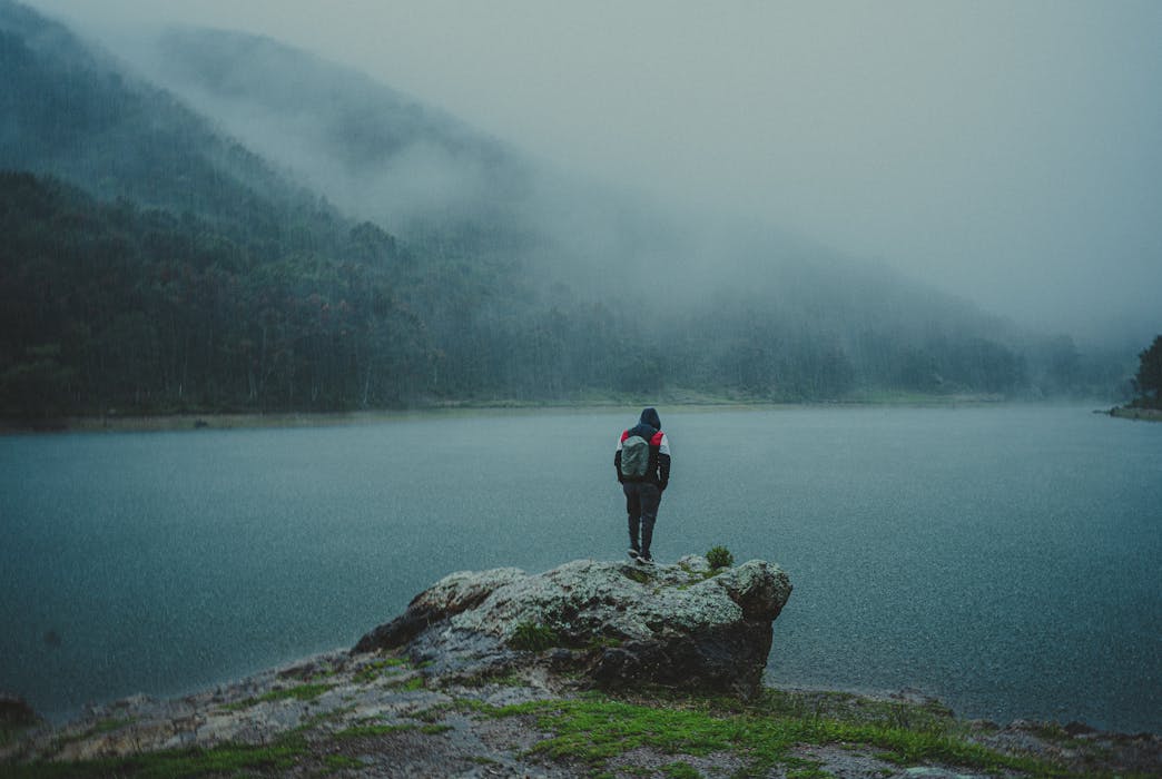 Man Standing on a Big Rock Beside a Lake