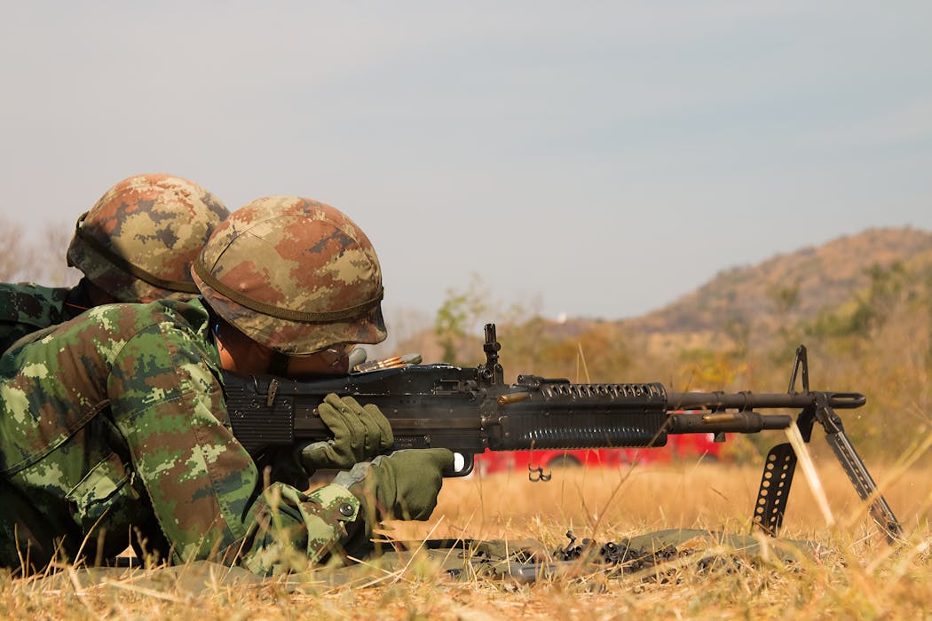 Man Lying Forward Using Rifle at the Field during Day