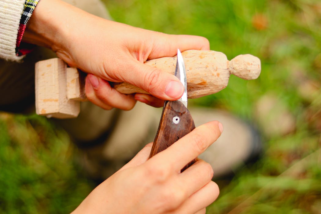 Close-Up of Hand Carving Wooden Figure Outdoors