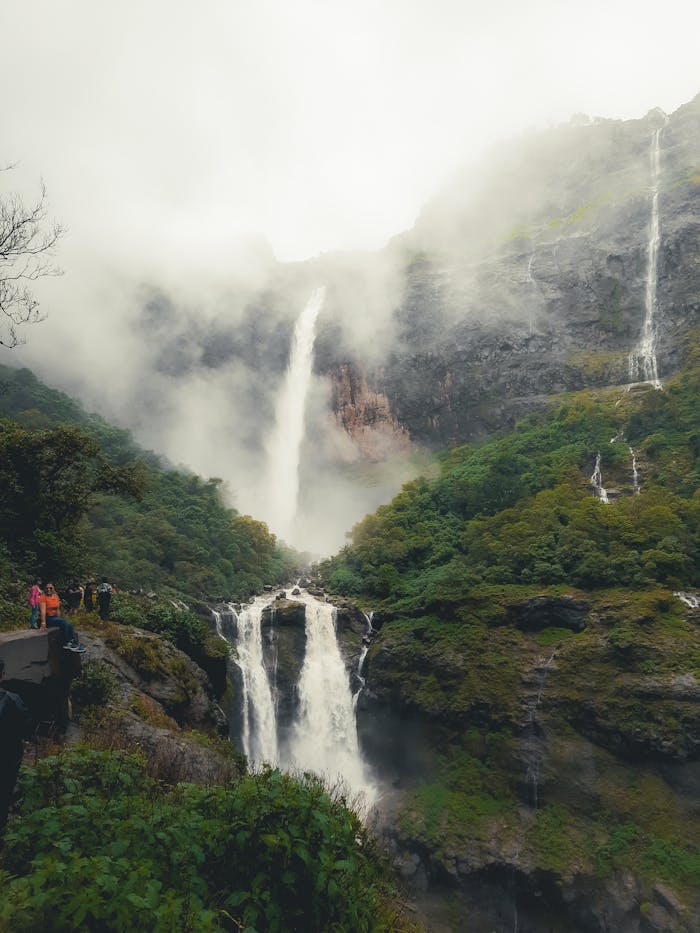 A waterfall in the mountains with fog and clouds
