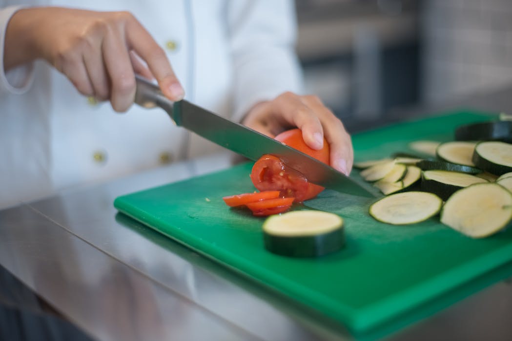 A Person Slicing a Tomato