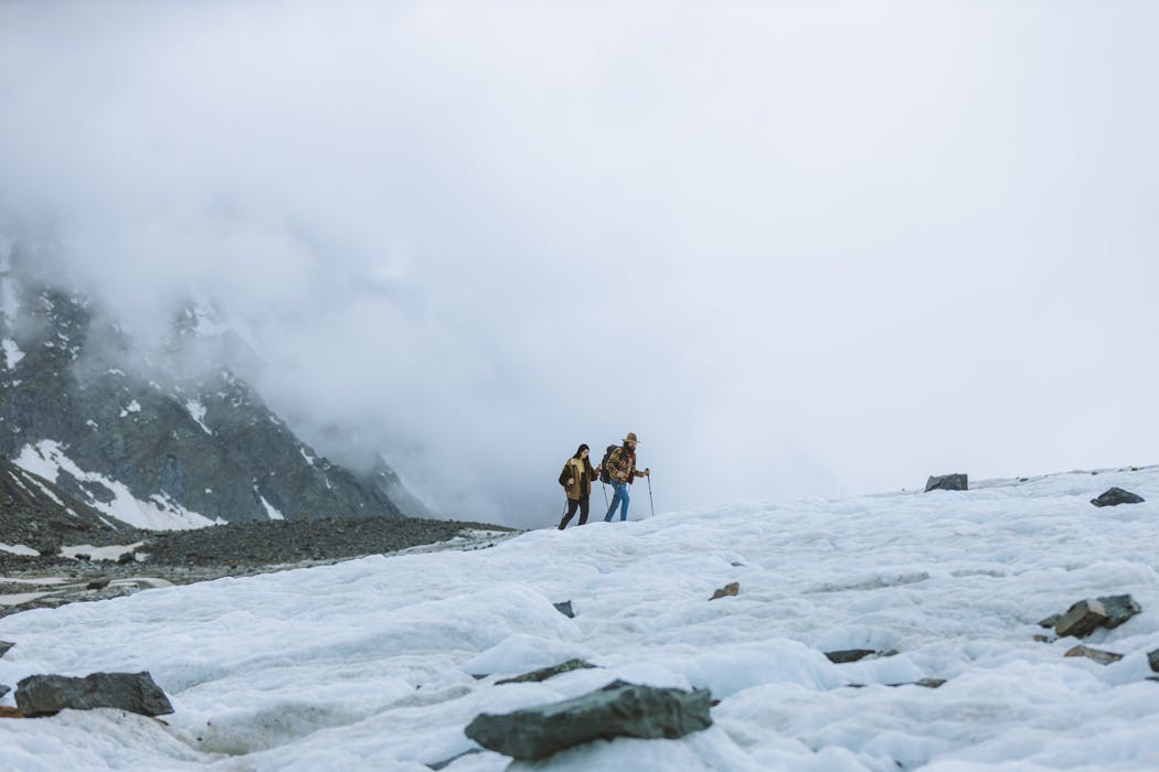 Two People Hiking in the Mountains with Snow and Fog