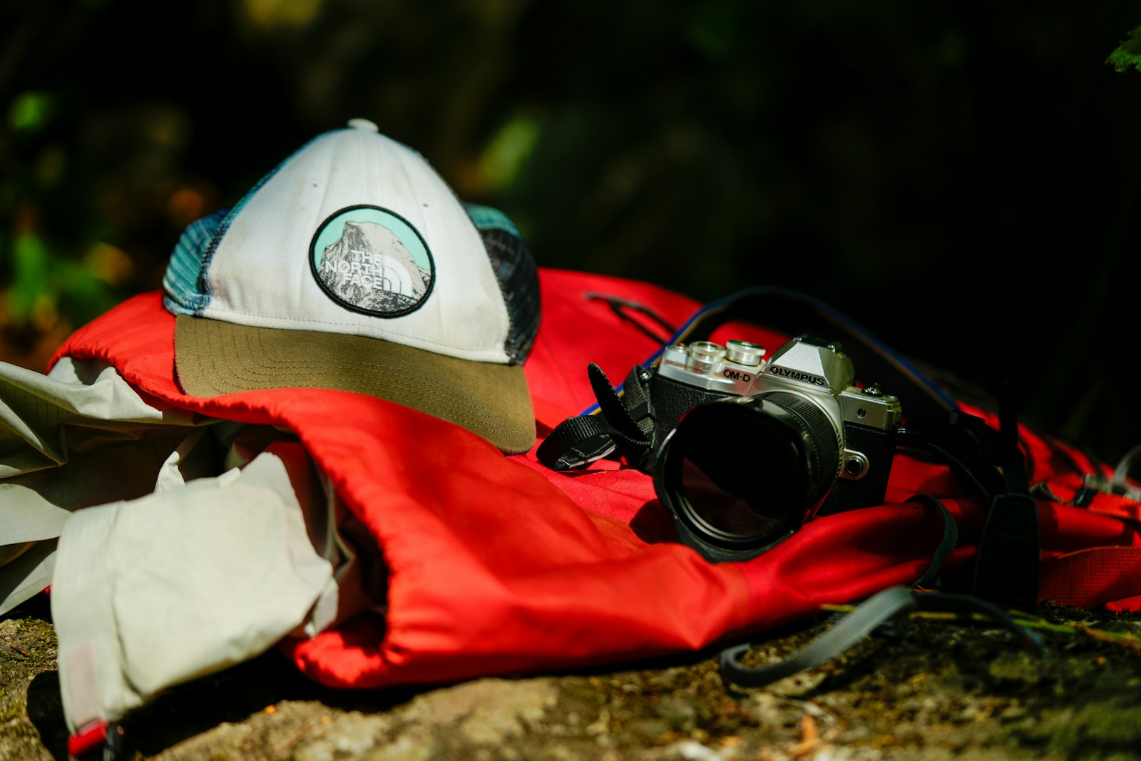 A pair of sunglasses and a hat laying on a rock