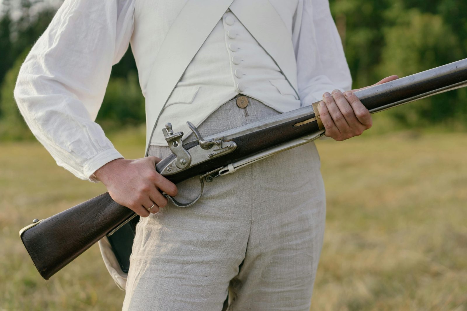 Close-up of a reenactor in historical soldier uniform with musket, outdoors.