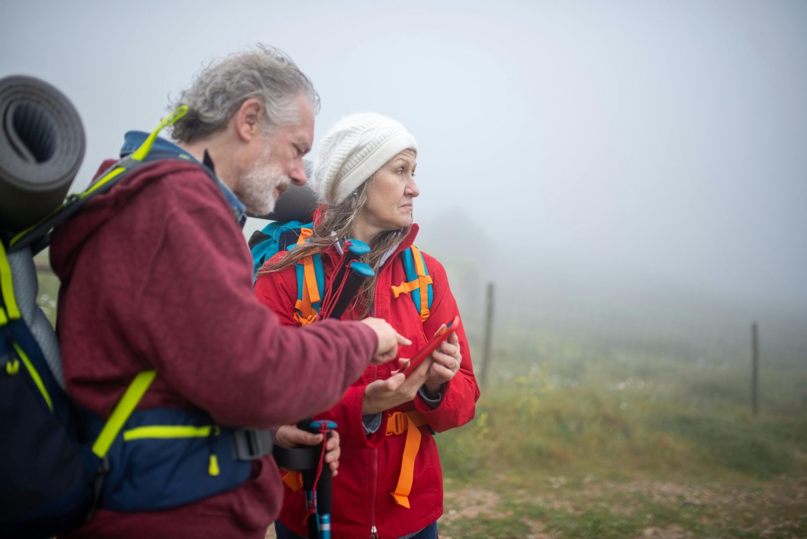 Two hikers consult a smartphone in a foggy rural landscape in Portugal.