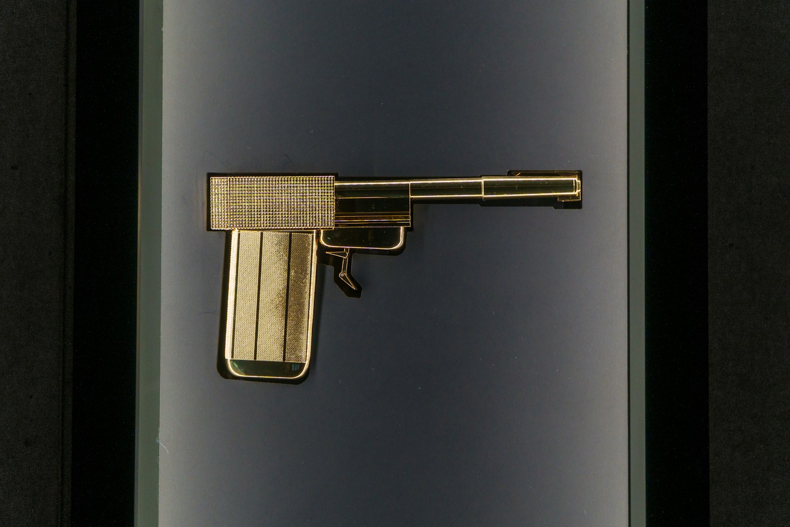 A golden pistol is displayed in a case.