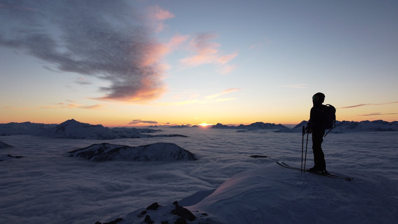 Person Skiing on Hilltop over Clouds in Winter