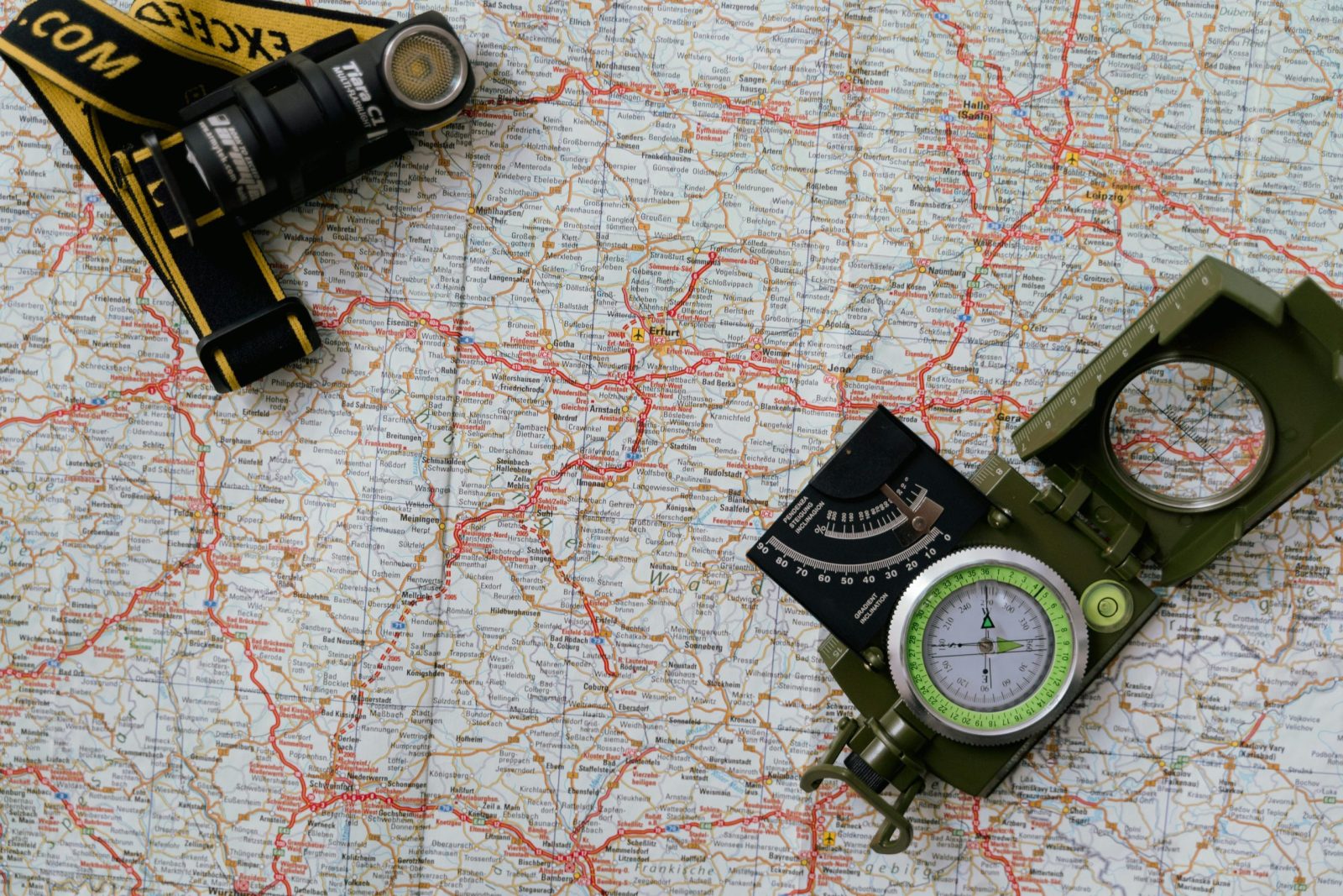 Overhead view of a map with a compass and flashlight showing navigation tools.