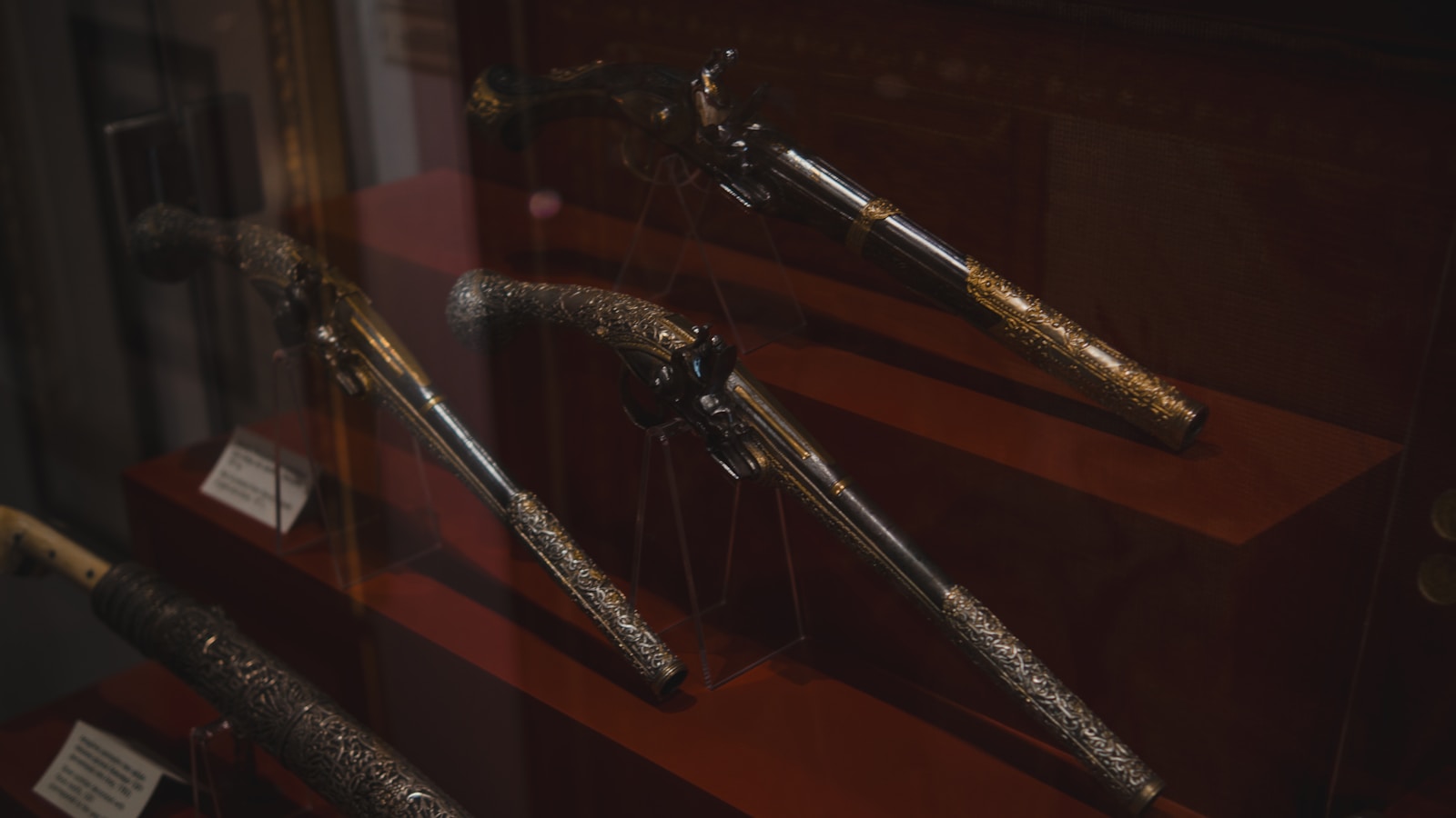 Antique ornate firearms displayed in a museum exhibit.